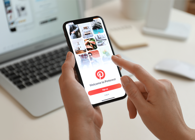 closeup of a smartphone in a person's hands with the pinterest login page on the screen
