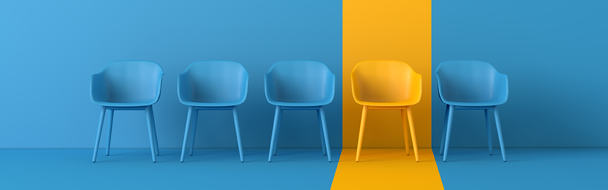 photo of five chairs on a blue background, with three blue chairs to the left, then one solitary yellow chair, and a final blue chair on the right