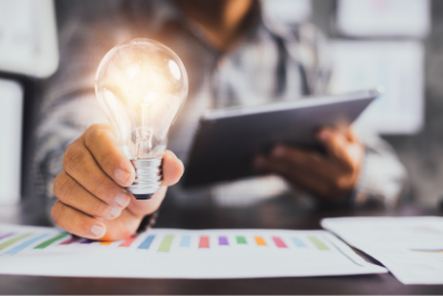 Lightbulb held in hand, lit up above marketing report