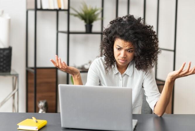 a black woman makes a confused gesture at a laptop